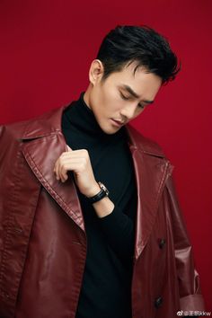 a man in a black turtle neck shirt and red leather jacket looking at his watch