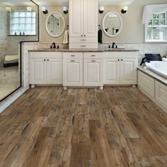 a large bathroom with wood floors and white cabinets