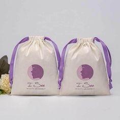 two bags with purple ribbon on them sitting next to flowers