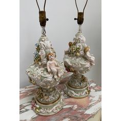 two lamps sitting on top of a table with an angel figurine next to them