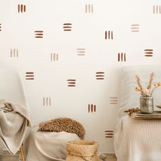 two white chairs sitting next to each other in front of a wall with brown circles on it