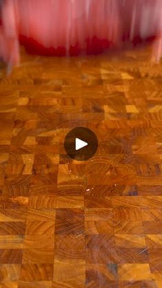 a close up of a wooden floor with a hole in the center and a red chair behind it