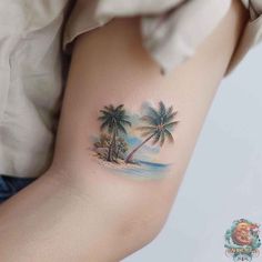 a woman's arm with a palm tree and beach scene tattoo on the left side