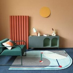 a living room with a blue rug and two green chairs in front of a wall mounted radiator