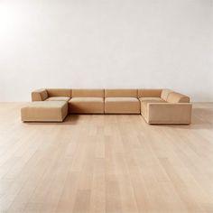 a large sectional couch sitting on top of a hard wood floor next to a white wall