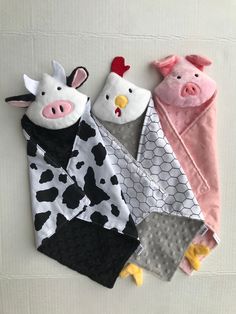 three farm animals are laying next to each other on the floor, one is wearing a cow costume