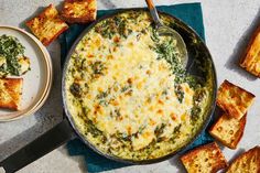 a casserole with spinach, cheese and bread on a blue towel next to it