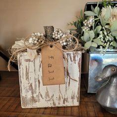 a wooden box with a tag on it sitting next to a metal duck and flowers