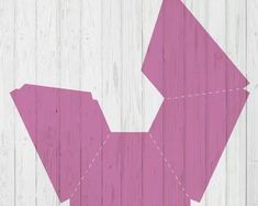 an origami piece is cut out on a white wooden background with pink lines