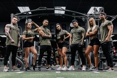 a group of people standing next to each other in front of a gym equipment rack