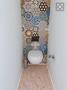 a bathroom with a toilet and colorful wallpaper on the walls, along with wooden flooring