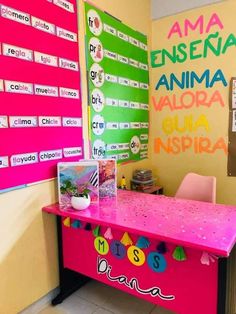 a pink desk sitting in front of a wall with spanish writing on it and pictures hanging up against the wall