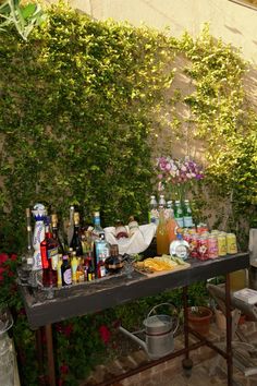 an outdoor table with bottles and drinks on it