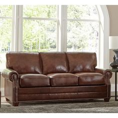 a brown leather couch sitting in front of a window