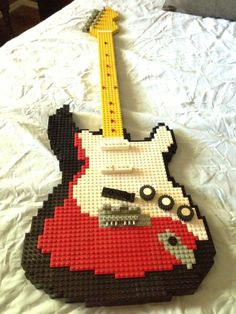 a guitar made out of legos sitting on top of a bed