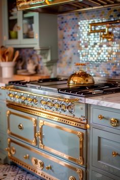 a kitchen with blue cabinets and gold trimmings on the stove top, along with an ornate tile backsplash