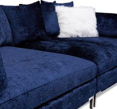 a blue velvet couch with white pillows on it's arm and backrests