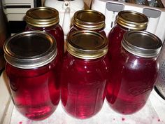 four jars filled with red liquid sitting on top of a counter