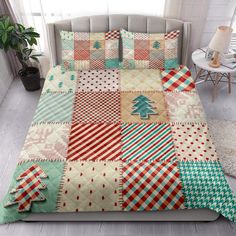 a bed covered in lots of different colored patchwork quilts and pillows with a christmas tree on it