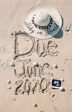 a hat, sunglasses and photo frame are written in the sand with words due june 2010