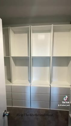 an empty room with white shelves and drawers