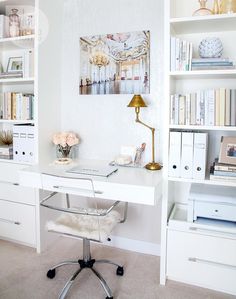 a home office with white bookcases and shelves filled with books, papers, and flowers