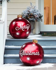 two red christmas baubles sitting on the steps next to each other in front of a house