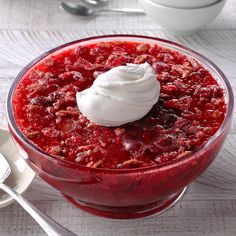 a dessert in a bowl with whipped cream on top and spoons next to it