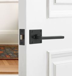 an open door with a black handle on it and a rug in the room next to it