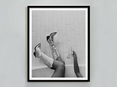 a black and white photo of two people laying in a bathtub with their feet up