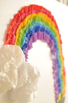 a rainbow made out of tissue paper sitting on top of a white table next to a roll of toilet paper