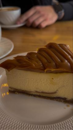 a piece of cheesecake with caramel drizzled on top sitting on a white plate