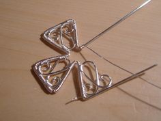 two pieces of silver wire sitting on top of a wooden table