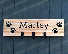 a wooden sign that says marley with paw prints on it and three black shoes hanging from the hooks