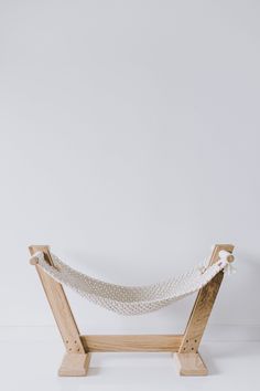 a wooden hammock stand with white fabric on the front and back sides, against a plain background