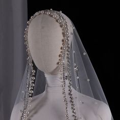 the back of a wedding dress with pearls and beads on it's headpiece