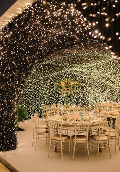 an outdoor dining area is lit up with fairy lights