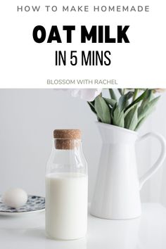 a glass bottle filled with milk next to a white vase and green plant on a table