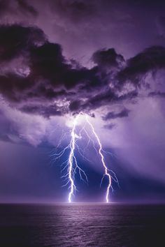 a lightning bolt is seen over the ocean