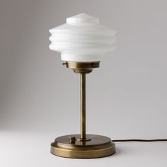 a table lamp with a white glass shade on it's base and a brown cord