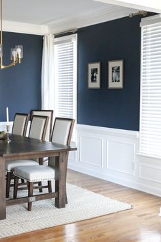 a dining room with blue walls and white trim on the windows, chairs and table