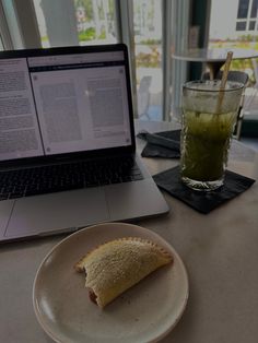 a laptop computer sitting on top of a table next to a plate with food and drink