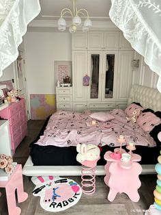 a bedroom decorated in pink and white with lots of toys on the floor, including a bed