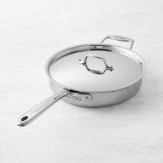 an aluminum pan with handle on a white countertop next to a knife and fork