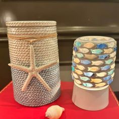 two vases sitting on top of a red table next to a starfish decoration