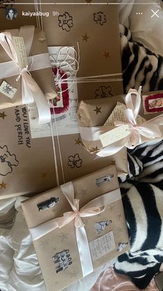 several wrapped presents are sitting on the bed with zebra print sheets and ribbons around them