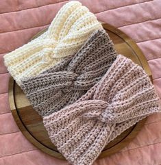 three knitted headbands sitting on top of a wooden plate