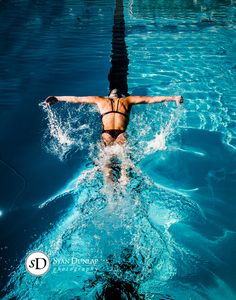 a woman is swimming in the pool with her arms outstretched and legs spread out,