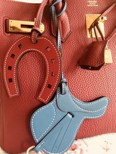 a red purse with a blue handle and some other items attached to the front of it