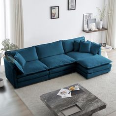 a living room with a blue sectional couch and coffee table in the middle, along with pictures on the wall